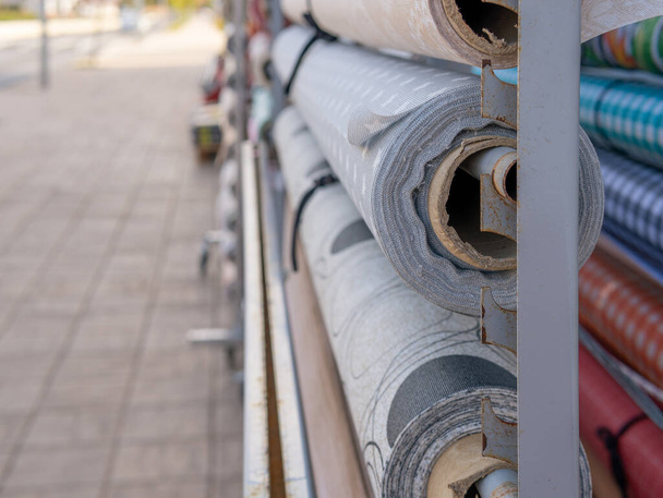Display of rolls of fabric and gift paper displayed outside a shop. Image with blurred background with bokeh effect - Photo, Image