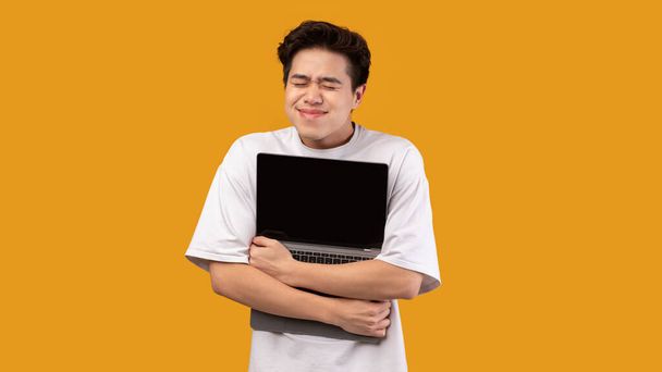 技術愛好家。アジア系の男がパソコンを抱いてる - 写真・画像
