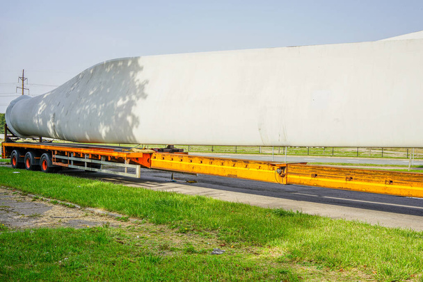 Widok ciężarówki, naczepy niskopodwoziowej z ponadgabarytowymi częściami generatora wiatru na parkingu - Zdjęcie, obraz