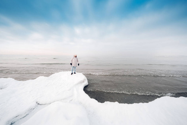 A tourist stands on the shore of the Baltic sea in winter. Winter near the Baltic States of Tallinn.Traveler near the sea in winter. - Foto, imagen