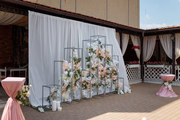 パステルカラーの花やキャンドルで飾られた公開幾何学的な結婚式のアーチ.  - 写真・画像