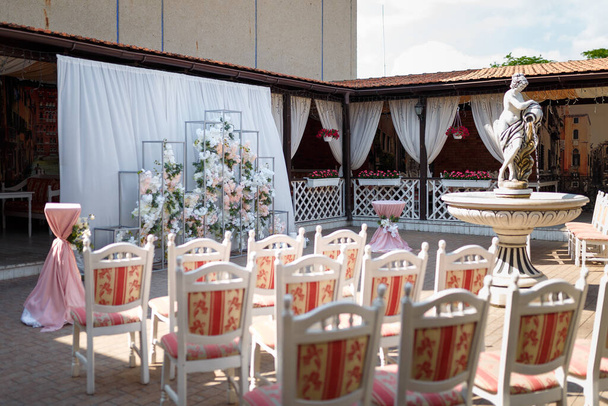 Křehký geometrický svatební oblouk zdobený květinami a svíčkami v pastelových barvách.  - Fotografie, Obrázek