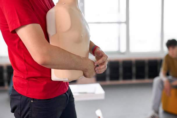 side view on male holding mannequin in hand durin first aid lesson - Photo, Image