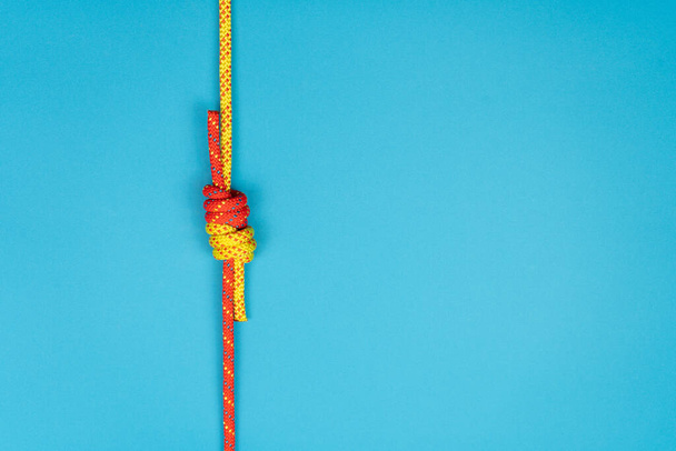 Рыбак узел с красной и желтой альпинистской верёвкой на синей бэкгро - Фото, изображение