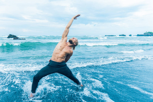 Athlete man practicing on a beach shore - Fotoğraf, Görsel