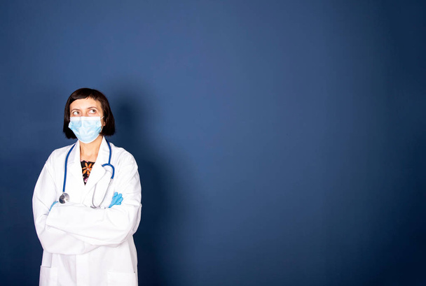 Medicine, profession and healthcare concept - close up of female doctor or scientist in protective facial mask over blue background - Foto, immagini