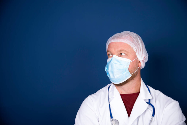 Medicine, profession and healthcare concept - close up of male doctor or scientist in protective facial mask over blue background - Foto, immagini
