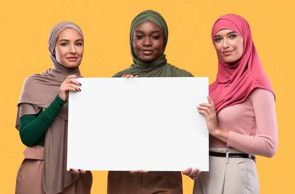 Three Muslim Women Holding Blank Board For Text, Yellow Background - Photo, image