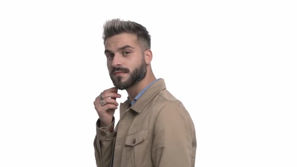 side view of sexy cool man in denim shirt pointing fingers and trying to remember, enthusiastically clapping, pointing finger to heart and inviting, isolated on white background in studio - Footage, Video