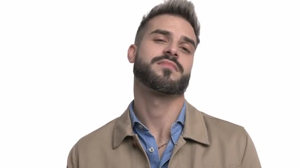 arrogante casual man in beige jas wijzende vingers naar het hoofd, lachen en kijken naar opzij, wijzende vingers en het maken van handgebaren, geïsoleerd op witte achtergrond in de studio - Video