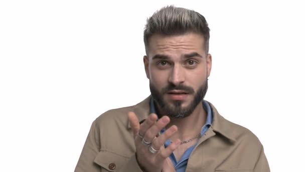 timid young fashion model in denim shirt rubbing palms, making surprised faces, taking a step back and making stop gestures on white background in studio - Footage, Video