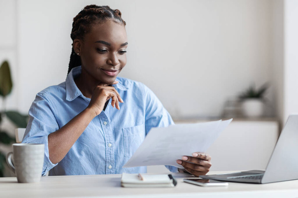 Femme entrepreneure noire ambitieuse travaillant avec la documentation commerciale au bureau - Photo, image