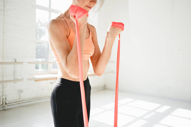 Strong slim sportswoman training body with elastic band. Fitness woman doing workout exercises resistance band - Valokuva, kuva