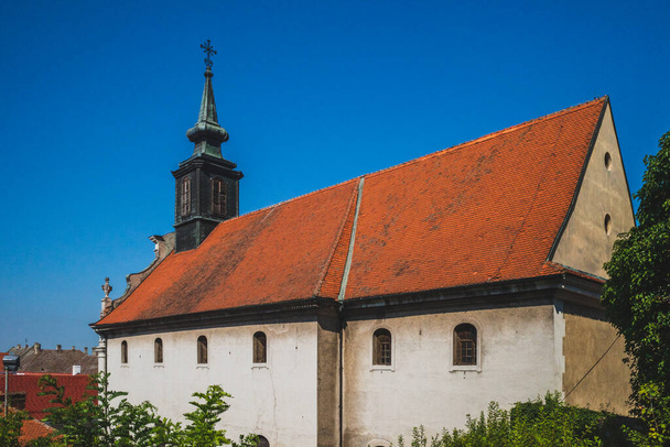 Kirche mit Turm in der Stadt Petrovaradin unter blauem Himmel in Novi Sad, Serbien - Foto, Bild