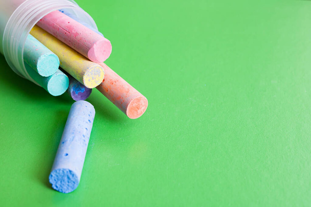 Container with multicolored crayons on a green background, copy space - Photo, Image