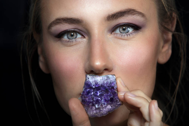 Closeup Portrait of a Gorgeous Woman Covered her Lips with Beautiful Purple Amethyst Stone. Fashion Silence. - Photo, image