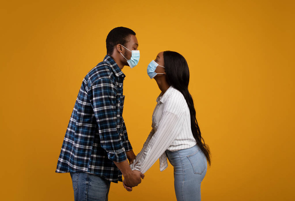 Африканські американські закохані в захисні маски хочуть поцілувати одне одного і триматися на віддалі. - Фото, зображення