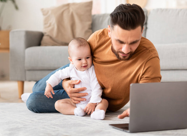 Πατέρας με το μικρό μωρό χρησιμοποιώντας το φορητό υπολογιστή περιήγηση στο Διαδίκτυο στο σπίτι - Φωτογραφία, εικόνα