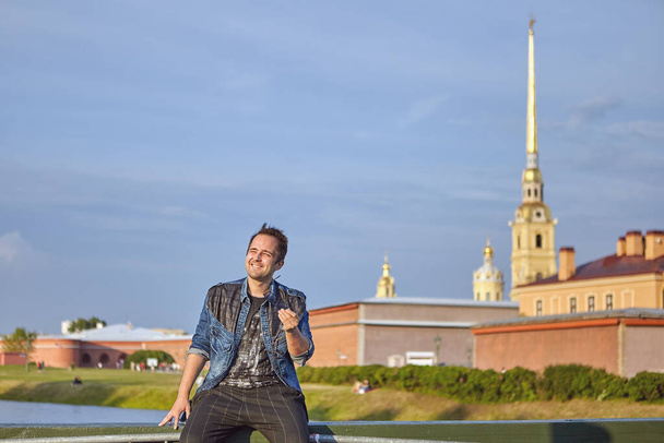 Uśmiechnięty biały człowiek siedzi w historycznym centrum Sankt-Petersburga, Rosja. - Zdjęcie, obraz