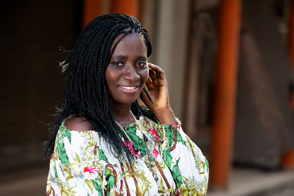 νεαρή Αφρικανή που στέκεται έξω κοιτάζοντας την κάμερα χαμογελώντας. - Φωτογραφία, εικόνα