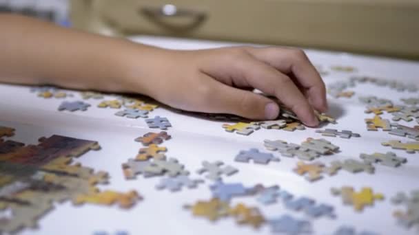 Dětské ruce sbírat puzzle na stole. Koncept vývoje dítěte. Close-Up - Záběry, video