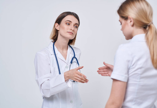 Medico professionista donna stringe la mano di una paziente su uno sfondo leggero - Foto, immagini