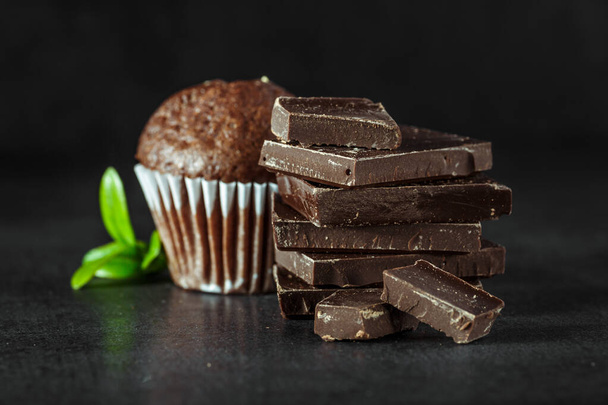 Chocolate cupcake with icing and chocolate bar in Dark lighting,Homemade delicious chocolate muffin on wooden background close-up - Foto, Imagem