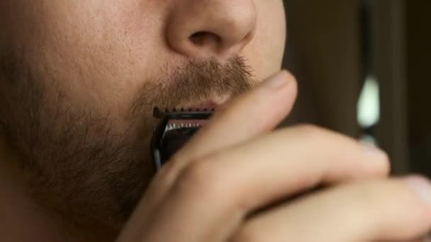 Cerca de hombre afeitando bigote y barba con una afeitadora eléctrica.  - Metraje, vídeo