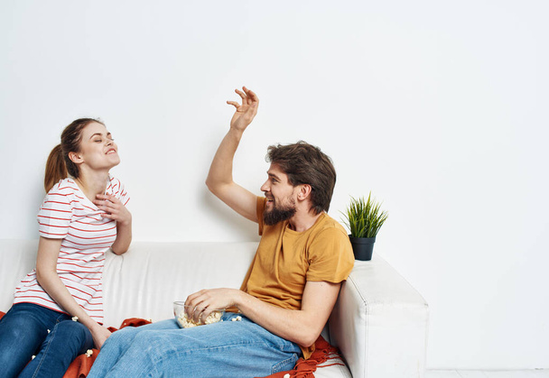 man and woman on the couch indoors chatting friends popcorn - 写真・画像