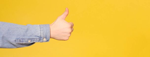 Male Hand Showing Thumbs Up Sign. Yellow background. Copy space - Φωτογραφία, εικόνα