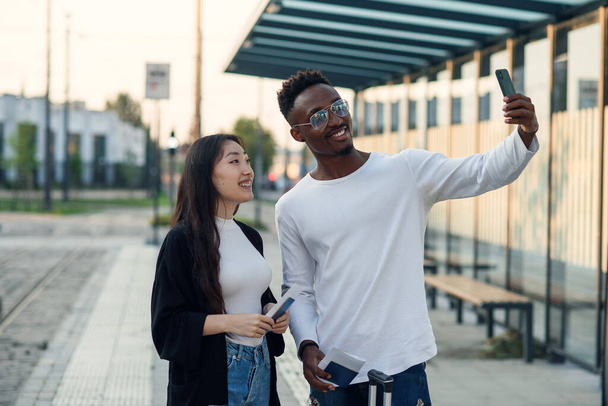 Cheerful multiracial male and female friends making selfie on smartphone with passports and tickets before joint trip. - Fotoğraf, Görsel