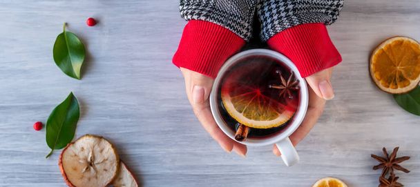 German tradition winter Christmas market new year holidays festival drink Gluhwein Mulled sweet hot warm red Wine in apple orange mug with spices citrus aromatic cinnamon star anise woman hand hold - Photo, image