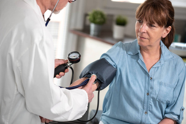 女性患者の血圧を測定する医師 - 写真・画像