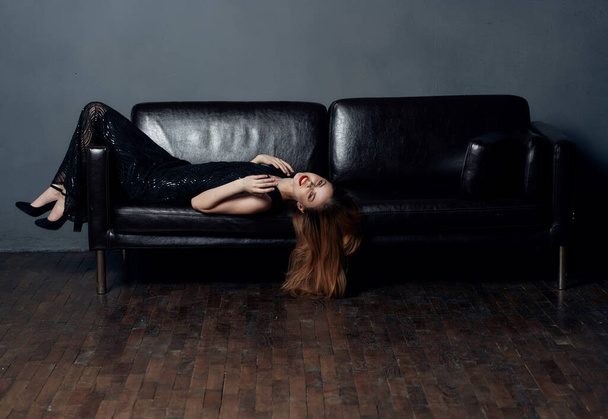Красива жінка з яскравим макіяжем лежить на шкіряному дивані крупним планом червона модель волосся
 - Фото, зображення