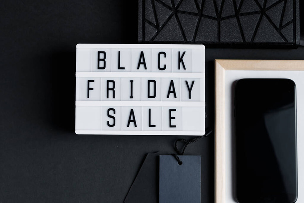 Black Friday sale. Smartphone and accessories on a dark background. Monochromatic flatlay, online shopping concept. - Photo, Image