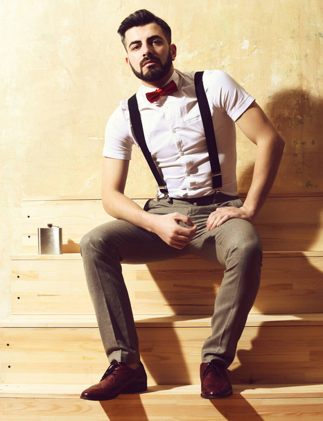 bearded man sitting on wooden stairs with serious face - Фото, зображення