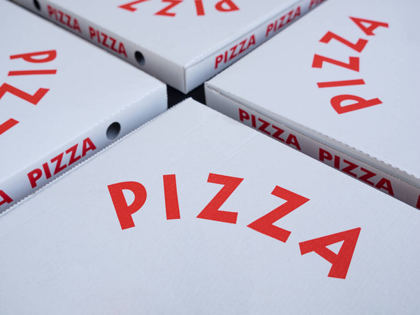 Quatre boîtes à pizza blanches avec des lettres rouges. Concentre-toi sur les lettres. Concept à emporter - Photo, image