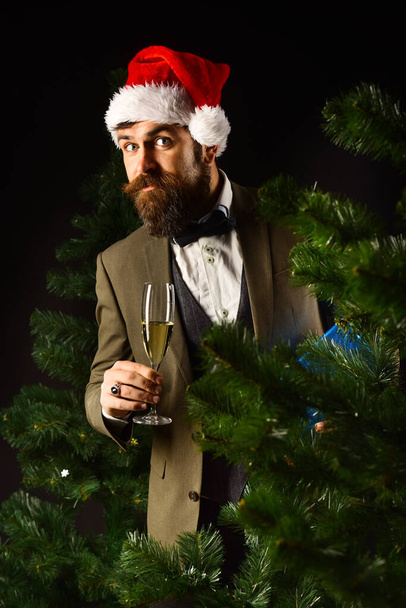 Businessman hiding behind christmas tree with champagne glass - Photo, image