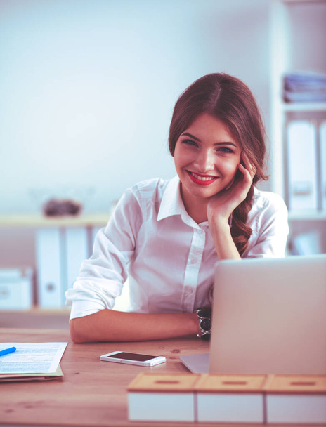 Attractive businesswoman sitting on desk in the office - Foto, Imagem