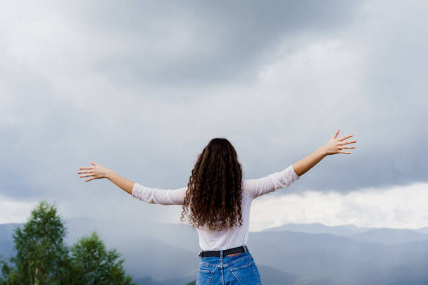 Poczucie wolności w Karpatach. Turystyka podróżuje po Ukrainie. Dziewczyna podniosła ręce do góry i cieszy się widokiem na wzgórza górskie. - Zdjęcie, obraz