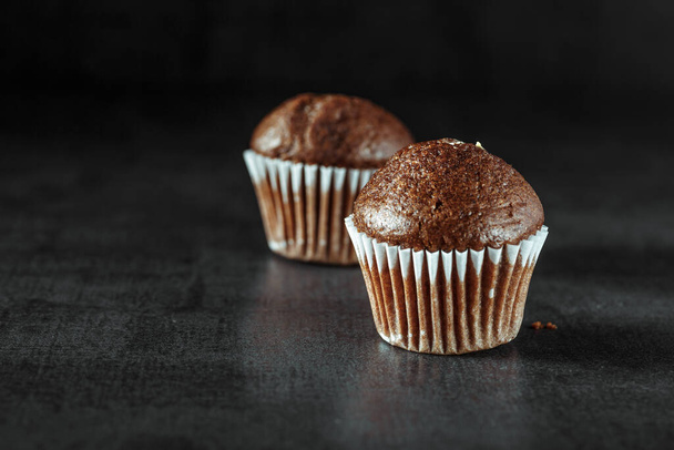 Chocolate cupcake with icing and chocolate bar in Dark lighting,Homemade delicious chocolate muffin on wooden background close-up - Foto, Bild