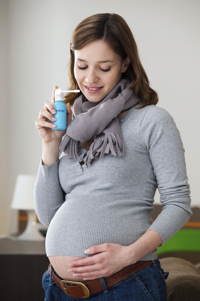 PREGNANT WOMAN USING SPRAY - Foto, imagen