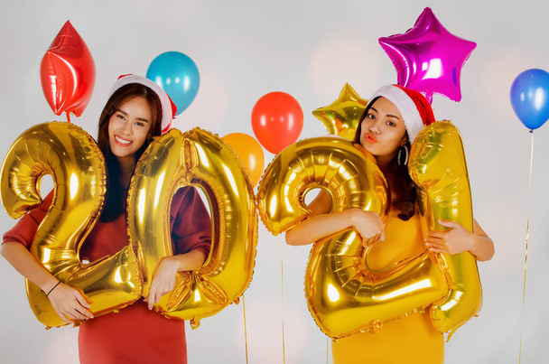 Amigo casal foto, bela menina asiática em vestido de festa de areia comemorando o ano novo, segurando balão número de ouro, 2021, celebração feriado ano novo de modelo encantador: Feliz Ano Novo e Natal - Foto, Imagem