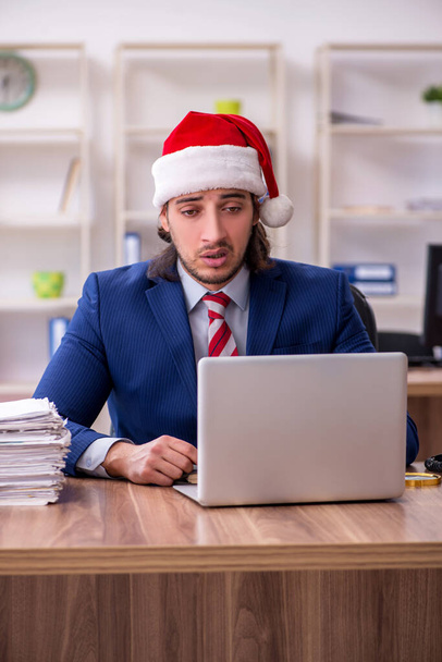 Noel arifesinde ofiste çalışan genç bir erkek işçi. - Fotoğraf, Görsel