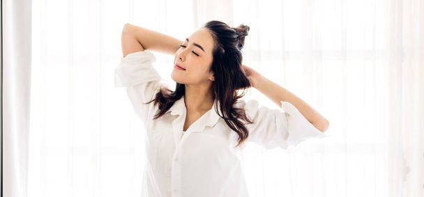 Usmívání veselý krásný pěkný asijský žena čistý svěží zdravý bílý kůže pózování v bílém oblečení.Dívka kácení relaxační a užívat si čas na posteli doma. - Fotografie, Obrázek