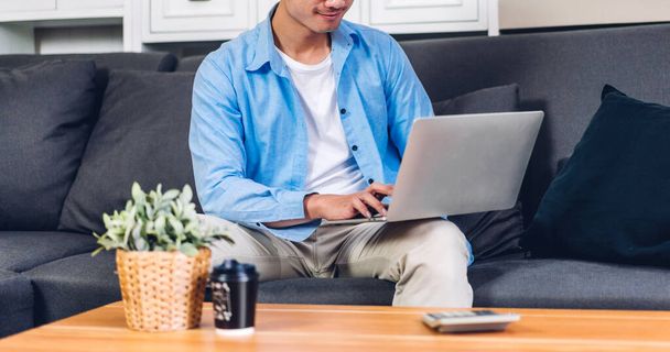 Fiatal mosolygós ázsiai férfi segítségével laptop számítógép munka és videó konferencia online találkozó kollégáival otthon.Fiatal kreatív férfi beszélgetés videó hívás üzleti team.work otthonról koncepció - Fotó, kép