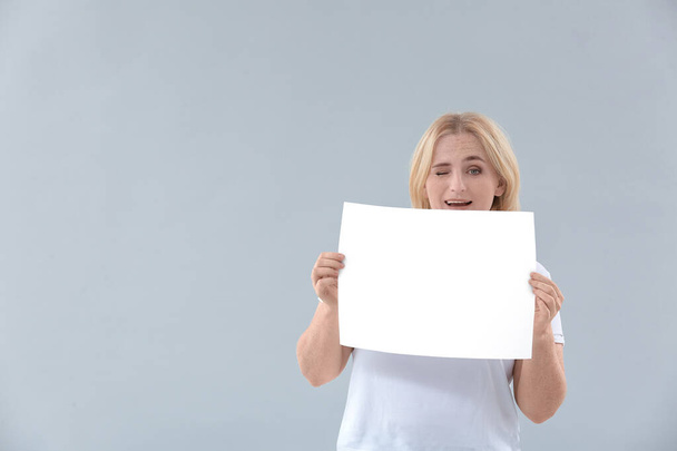 Woman with blank paper sheet on grey background - Fotoğraf, Görsel