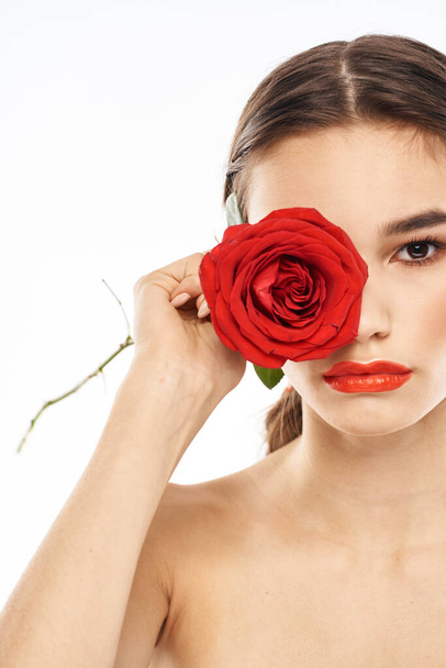 γοητευτικό μελαχρινή κοπέλα με μακιγιάζ στο πρόσωπό της και ένα κόκκινο τριαντάφυλλο στο χέρι - Φωτογραφία, εικόνα