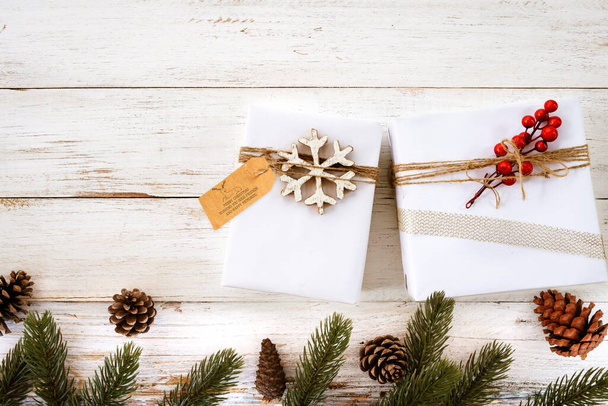 Coffret cadeau de Noël avec étiquette de vœux - cadeau de Noël et décoration de feuilles de pin sur table en bois blanc. Joyeux Noël et Nouvel An fond de vacances. vue de dessus. - Photo, image