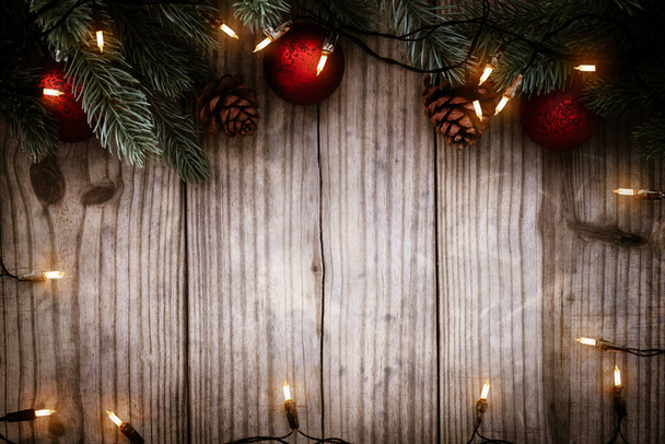 Kerstachtergrond - Kerstverlichting bol en dennenbladeren decoratie op houten tafel, frame border design. Vrolijk Kerstfeest en Nieuwjaar vakantie achtergrond. bovenaanzicht. - Foto, afbeelding